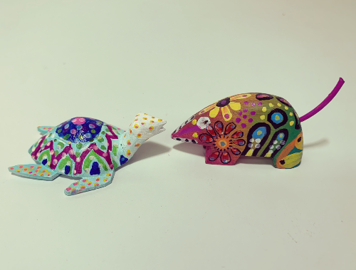 two small alebrijes painted with colorful designs