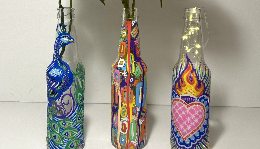 Three glass bottles painted with colorful designs