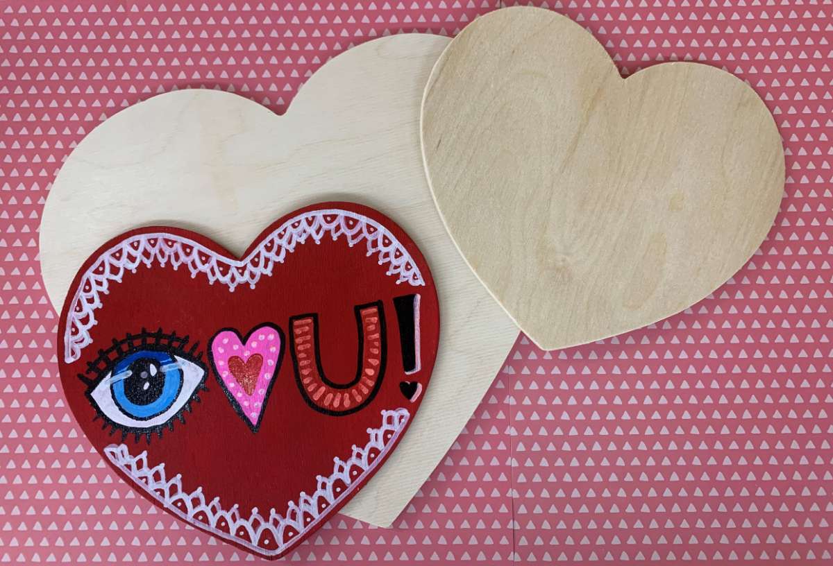 multiple wooden hearts on a table included one painted one.